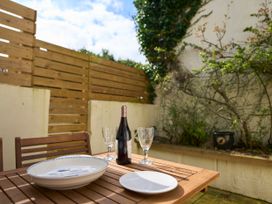 An outdoor wooden table with plates wine bottle and glasses next to a wooden fence and plants at Saltwater Cottage in Babbacombe