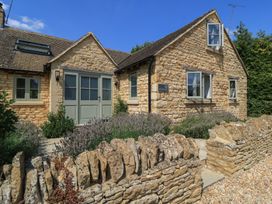 The exterior of a house with a stone wall and garden at 12 Manor Farm Close Kingham