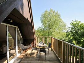 A balcony with a small round table and four chairs overlooking trees at 60 Valley Lodge in Callington near Gunnislake