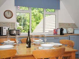 A kitchen with a wooden dining table set with bowls and glasses and blue cabinets at 60 Valley Lodge Callington near Gunnislake