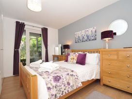 A bedroom with a wooden bed and dresser purple curtains and floral bedding at 60 Valley Lodge in Callington near Gunnislake