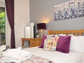 A bedroom with a wooden bed frame purple and floral cushions bedside table with lamp and mirror at 60 Valley Lodge Callington near Gunnislake