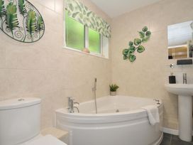 A bathroom with a corner bathtub a toilet a pedestal sink and leaf decorations on the wall at 60 Valley Lodge Callington near Gunnislake