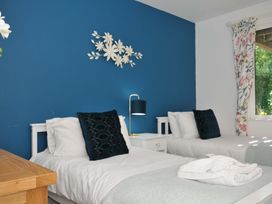 A bedroom with two single beds a wooden desk and a window with floral curtains at 60 Valley Lodge in Callington near Gunnislake