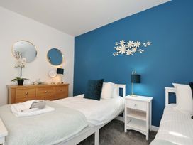 A bedroom with two single beds a wooden dresser with mirrors and a blue accent wall with white flower decorations at 60 Valley Lodge Callington near Gunnislake