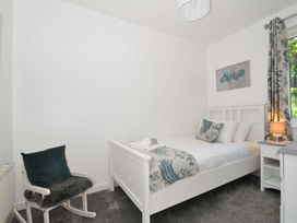 A bedroom with a white bed a rocking chair and a window at 60 Valley Lodge in Callington near Gunnislake