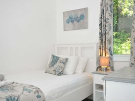 A bedroom with a white bed and floral cushion a bedside table with lamp and floral curtains at 60 Valley Lodge in Callington near Gunnislake