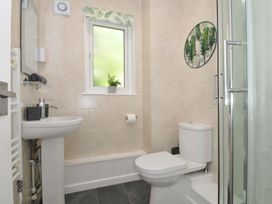 A bathroom with a sink a toilet a shower and a window with a plant at 60 Valley Lodge in Callington near Gunnislake
