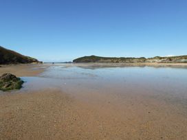 A beach with water and hills at Porth Cove in Porth