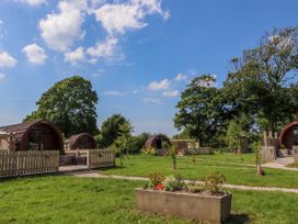 Outdoor area with wooden pods and small fenced patios on green grass with trees in the background at Lapwing Lodge in Cockerham near Lancaster