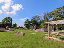 Small wooden pods in a grassy area with pathways and trees at Lapwing Lodge in Cockerham near Lancaster