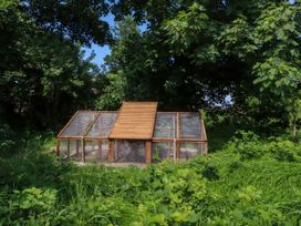 A wooden and wire mesh animal enclosure surrounded by grass and trees at Lapwing Lodge in Cockerham near Lancaster