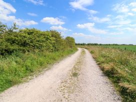 A dirt road with grass and bushes on both sides under a partly cloudy sky at Lapwing Lodge in Cockerham near Lancaster