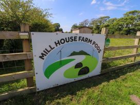 A sign on a wooden fence reading Mill House Farm Pods with fields and pod illustrations at Mill House Farm Pods in Cockerham near Lancaster