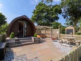 An outdoor area with a wooden pod cabin picnic table fire pit and hot tub at Lapwing Lodge in Cockerham near Lancaster