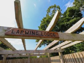 A wooden pergola with a sign reading Lapwing Lodge and trees in the background at Lapwing Lodge in Cockerham near Lancaster