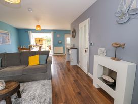 A living room with a sofa and dining area at Cae Berllan in Mynytho near Pwllheli