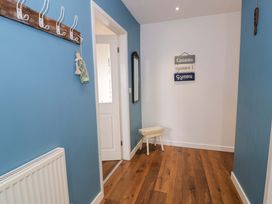 A hallway with coat hooks and a mirror at Cae Berllan in Mynytho near Pwllheli