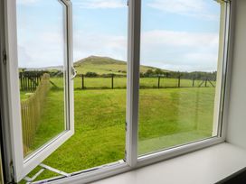 A view from a window showing grass and a hill at Cae Berllan in Mynytho near Pwllheli