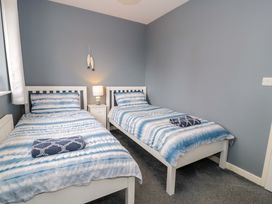 A bedroom with two single beds and a bedside table at Cae Berllan in Mynytho near Pwllheli