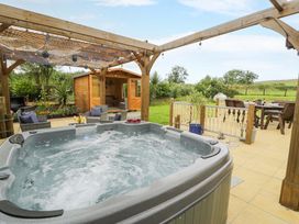 A garden with a hot tub and wooden shed at Cae Berllan in Mynytho near Pwllheli