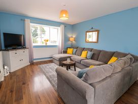 A living room with a sofa and television at Cae Berllan in Mynytho near Pwllheli