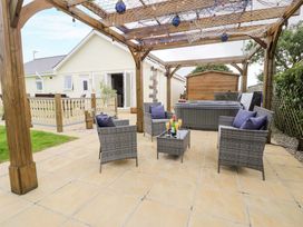 An outdoor patio with seating and a hot tub at Cae Berllan in Mynytho near Pwllheli