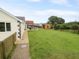 A garden with a house, patio set, and shed at Cae Berllan in Mynytho near Pwllheli