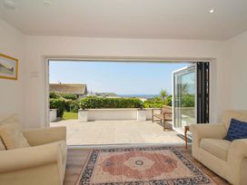 A living room with a view of the patio and ocean at Sunset in Polzeath