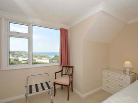 A bedroom with a window and chair at Sunset in Polzeath