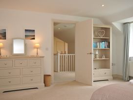 A bedroom with a dresser and open bookshelf at Farlands in Daymer Bay