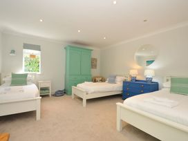 A bedroom with three beds and a blue dresser at Farlands in Daymer Bay