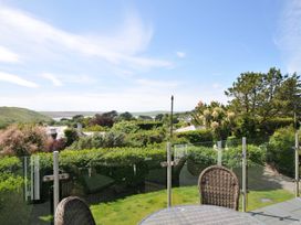 An outdoor area with a table and chairs overlooking a garden at Farlands Daymer Bay