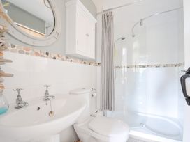 A bathroom with a sink, toilet, shower, and mirror at Rocklings, Rock