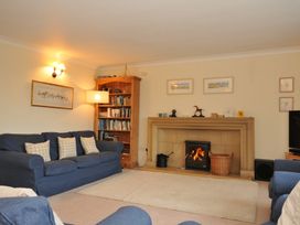 A living room with a fireplace and bookshelf at Tregillan in Rock
