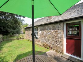 A garden with a wooden table and green umbrella at Mill Pond Rock