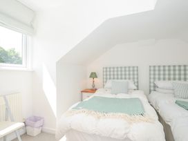 A bedroom with two beds and a lamp on a nightstand at Porthilly Brook in Rock