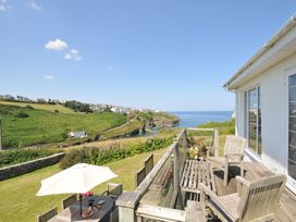 A terrace with a table and chairs overlooking the ocean at Cartway Cove, Port Isaac