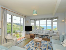 A living room with a sofa, tv, and coffee table at Cartway Cove in Port Isaac