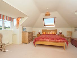A bedroom with a bed, dresser, and windows at Cartway Cove, Port Isaac