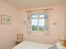 A bedroom with a window and chair at Cartway Cove in Port Isaac