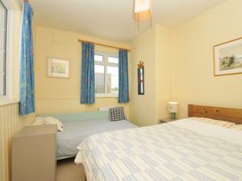 A bedroom with two beds and a window at Cartway Cove in Port Isaac