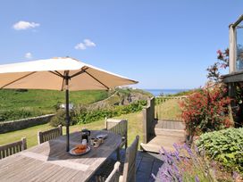 An outdoor dining area with a table and umbrella at Cartway Cove, Port Isaac