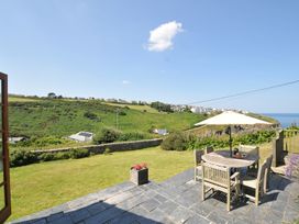 A patio with a table and chairs overlooking a garden at Cartway Cove in Port Isaac