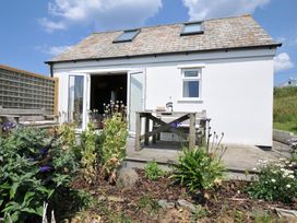 An outdoor view of a cabin with a table and flowers at Cartway Cabin Port Isaac