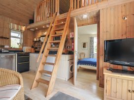 A living room with kitchen, staircase, and bed at Cartway Cabin, Port Isaac