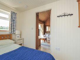 A bedroom with a bed and a doorway to another room at Cartway Cabin, Port Isaac