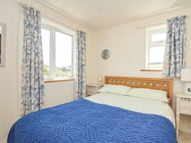 A bedroom with a bed and curtains at Cartway Cabin in Port Isaac