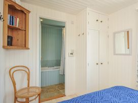 A bedroom with a closet, chair, and mirror at Cartway Cabin Port Isaac