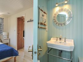 A bathroom with a sink and mirror at Cartway Cabin, Port Isaac